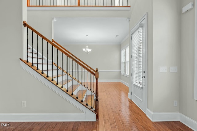 entrance foyer featuring hardwood / wood-style flooring, a notable chandelier, and ornamental molding