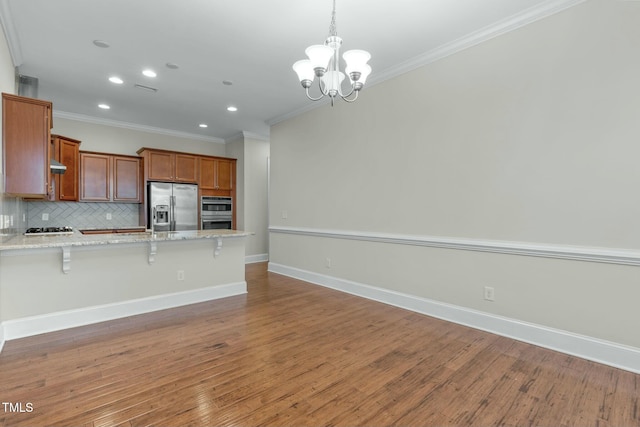 kitchen with decorative backsplash, appliances with stainless steel finishes, crown molding, a chandelier, and a breakfast bar area