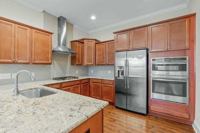 kitchen featuring light stone countertops, appliances with stainless steel finishes, tasteful backsplash, wall chimney exhaust hood, and sink