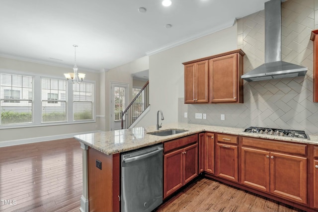 kitchen featuring wall chimney range hood, tasteful backsplash, a notable chandelier, pendant lighting, and appliances with stainless steel finishes