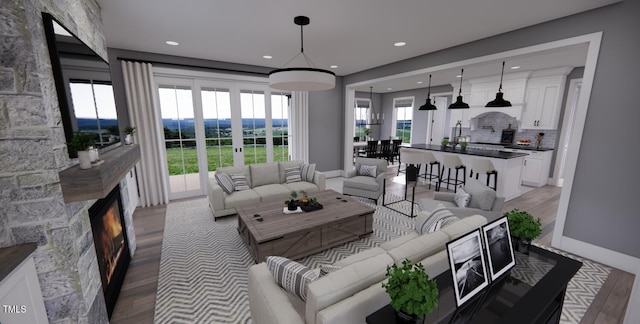 living room featuring wood-type flooring, plenty of natural light, and a stone fireplace