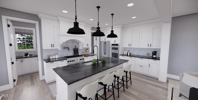 kitchen with white cabinets, a kitchen island with sink, sink, and decorative backsplash