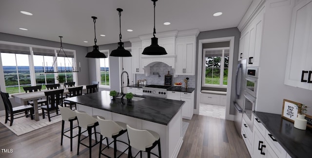 kitchen with sink, pendant lighting, white cabinetry, and a center island with sink