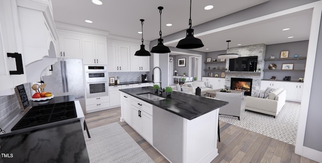 kitchen featuring tasteful backsplash, a center island with sink, sink, white appliances, and white cabinets