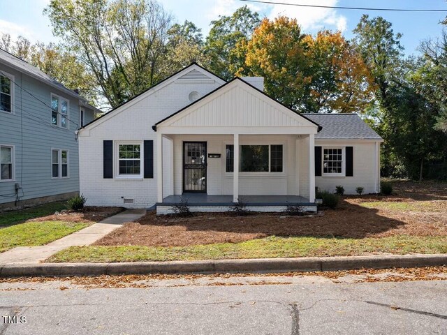 view of front of home featuring brick siding, covered porch, roof with shingles, and crawl space