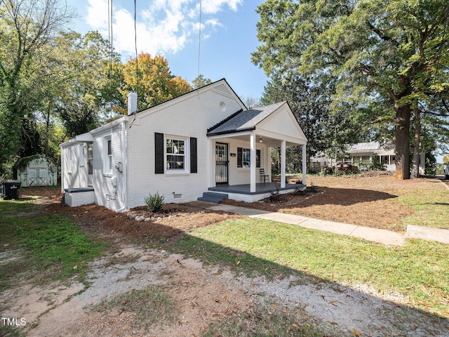 view of front of house featuring brick siding, covered porch, and a chimney