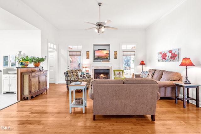 living room with light wood-type flooring, ceiling fan, and crown molding