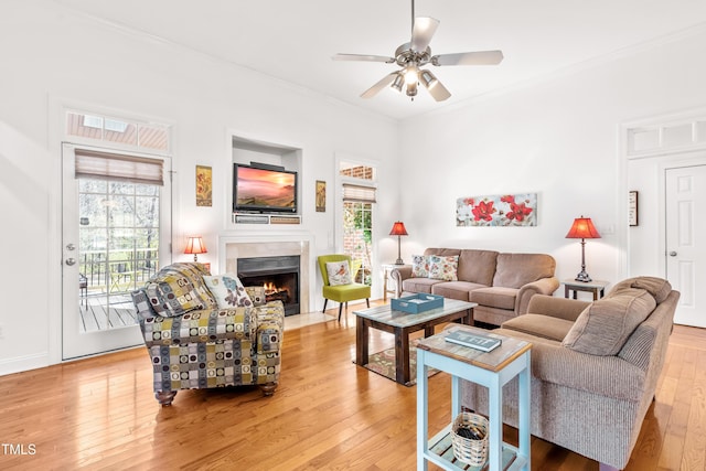 living room with light wood-type flooring, ceiling fan, ornamental molding, and a healthy amount of sunlight