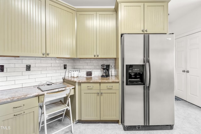 kitchen featuring stainless steel fridge with ice dispenser, light stone counters, and tasteful backsplash