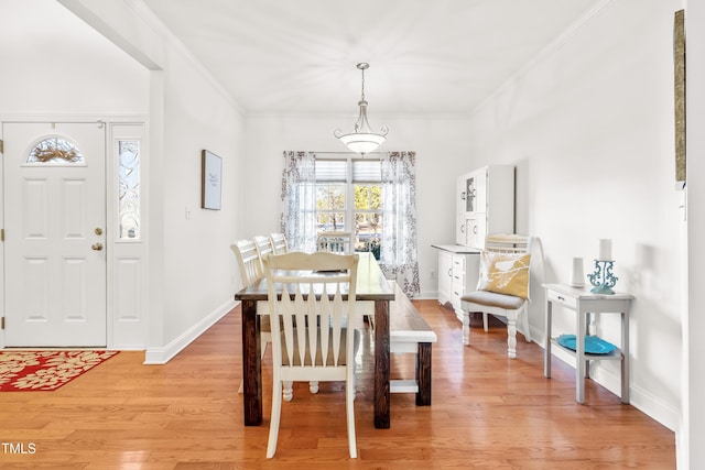 dining area with ornamental molding and light hardwood / wood-style floors