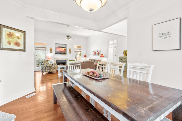 dining space with ceiling fan, crown molding, and wood-type flooring