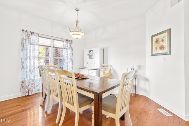 dining area with light hardwood / wood-style floors and crown molding