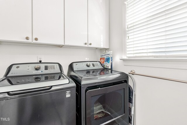 clothes washing area featuring washer and clothes dryer and cabinets