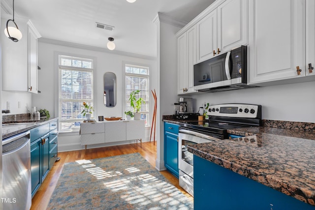 kitchen featuring appliances with stainless steel finishes, ornamental molding, white cabinets, and blue cabinets