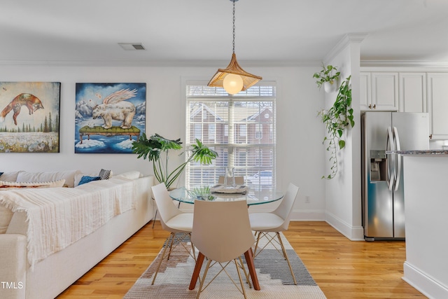 dining space featuring ornamental molding and light hardwood / wood-style flooring