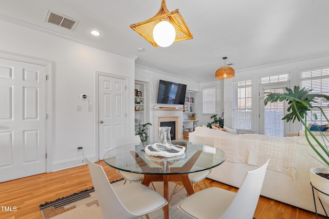 dining area featuring light wood-type flooring and crown molding