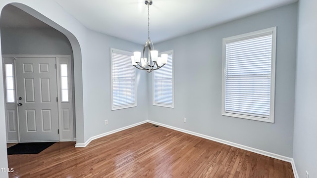 entryway with hardwood / wood-style floors, plenty of natural light, and a notable chandelier