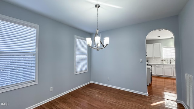 unfurnished dining area with a notable chandelier, dark wood-type flooring, and sink