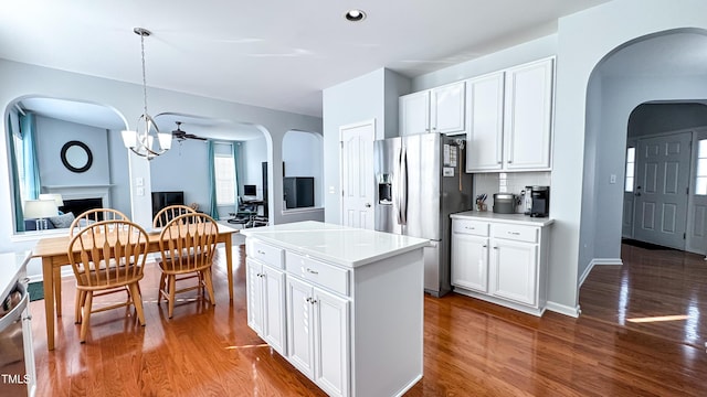 kitchen featuring hanging light fixtures, stainless steel refrigerator with ice dispenser, white cabinetry, and a kitchen island