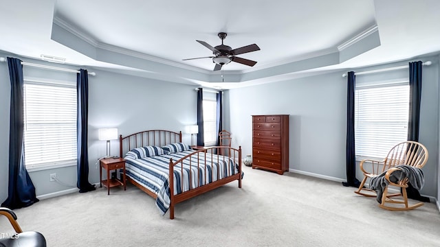 carpeted bedroom with a raised ceiling, ceiling fan, ornamental molding, and multiple windows