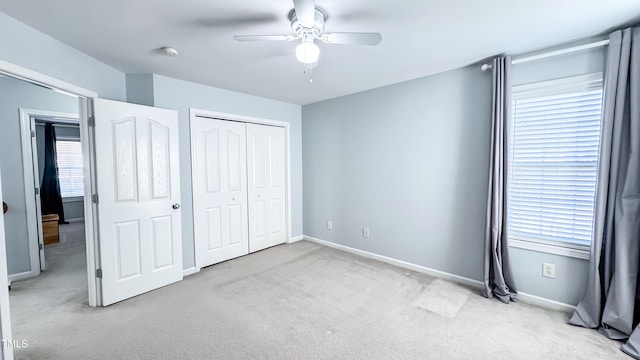 unfurnished bedroom with ceiling fan, light colored carpet, multiple windows, and a closet