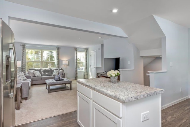 kitchen featuring lofted ceiling, dark hardwood / wood-style floors, stainless steel fridge, a kitchen island, and white cabinetry