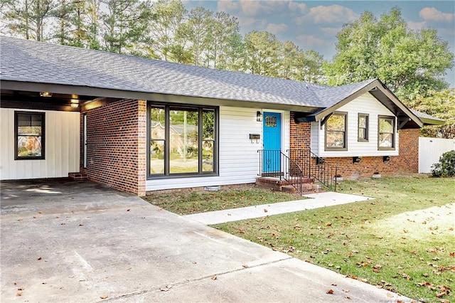 ranch-style home featuring a front lawn and a carport