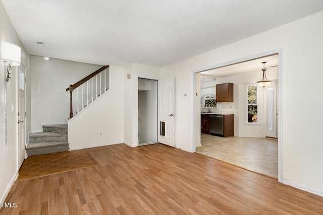 unfurnished living room featuring light hardwood / wood-style floors and a textured ceiling