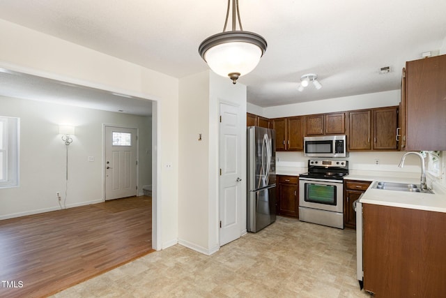 kitchen featuring hanging light fixtures, light wood-type flooring, sink, and appliances with stainless steel finishes