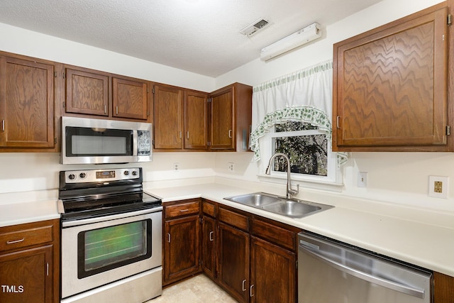 kitchen with stainless steel appliances, sink, and a textured ceiling