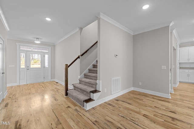 foyer entrance featuring crown molding and light hardwood / wood-style flooring