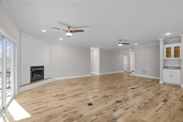 unfurnished living room with a fireplace, ceiling fan, light hardwood / wood-style floors, and crown molding