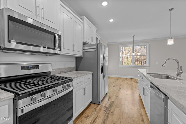 kitchen featuring stainless steel appliances, crown molding, light stone counters, sink, and white cabinetry