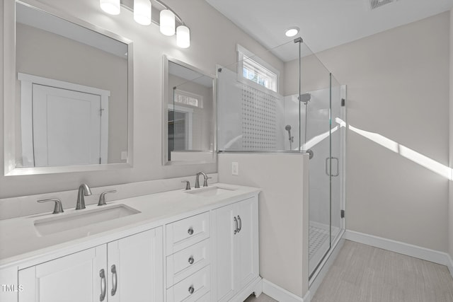 bathroom featuring a shower with door and vanity