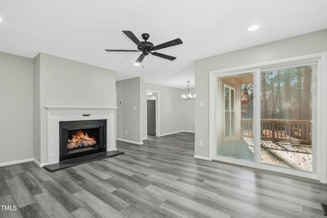 unfurnished living room with ceiling fan with notable chandelier and wood-type flooring