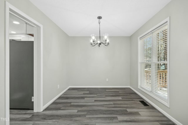 unfurnished dining area with dark hardwood / wood-style floors and an inviting chandelier