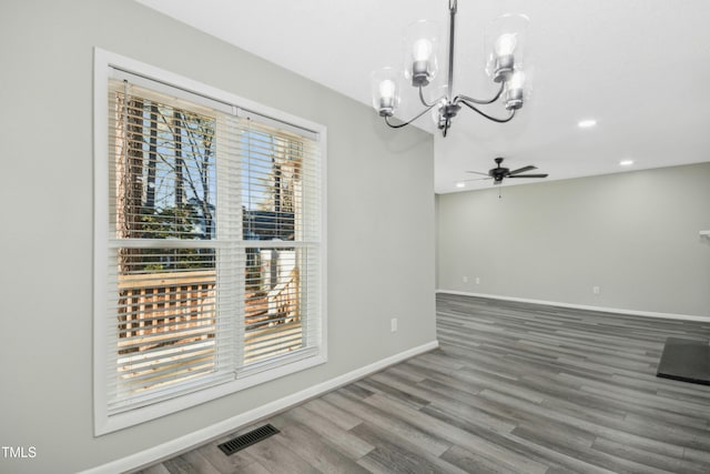 unfurnished dining area with ceiling fan with notable chandelier and hardwood / wood-style floors