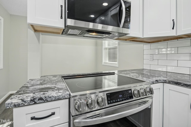 kitchen featuring kitchen peninsula, appliances with stainless steel finishes, stone countertops, and white cabinetry