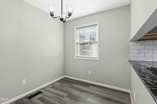 unfurnished dining area with dark hardwood / wood-style flooring and a notable chandelier