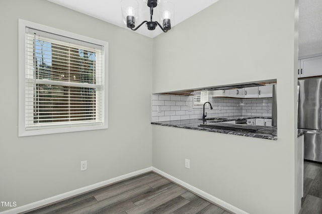 kitchen with decorative backsplash, stainless steel refrigerator, pendant lighting, white cabinets, and sink