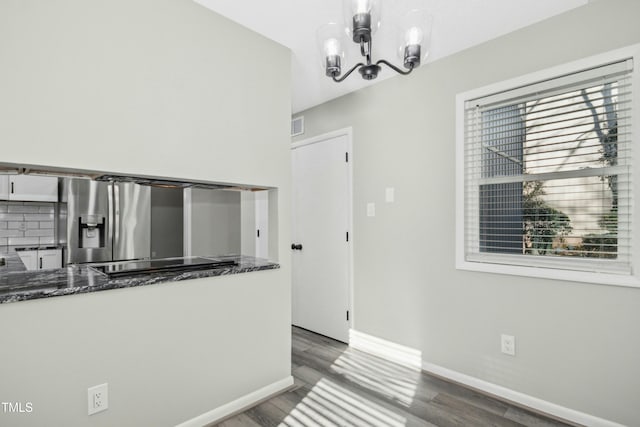 kitchen with a notable chandelier, hanging light fixtures, dark wood-type flooring, white cabinets, and stainless steel fridge