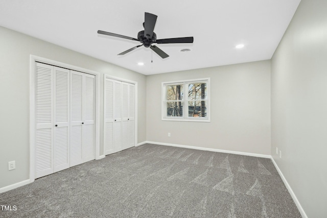 unfurnished bedroom with ceiling fan, two closets, and carpet floors