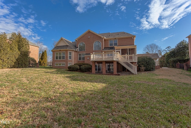 rear view of house with a wooden deck, a sunroom, and a yard