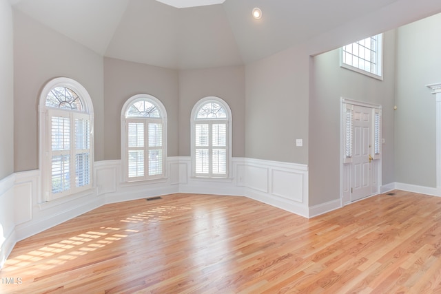 spare room with high vaulted ceiling and light wood-type flooring