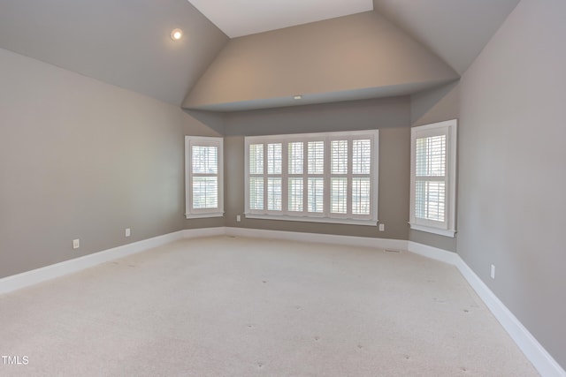 spare room featuring lofted ceiling and light colored carpet