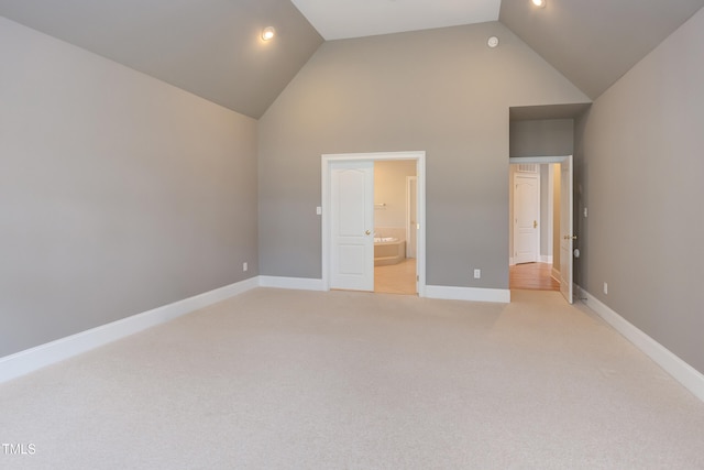 unfurnished bedroom featuring connected bathroom, light colored carpet, and high vaulted ceiling