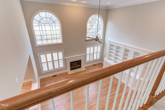 staircase featuring ornamental molding, a fireplace, and hardwood / wood-style floors