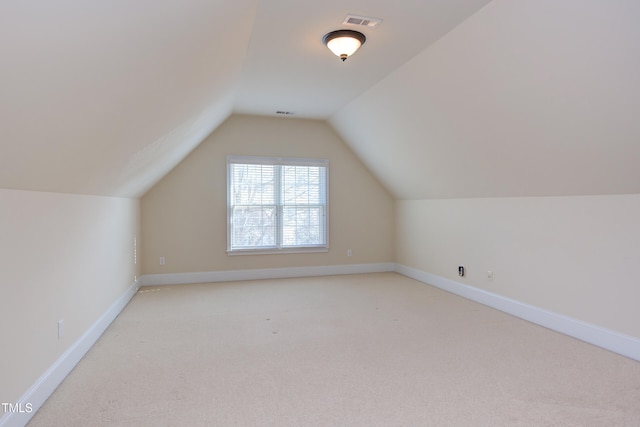 bonus room with vaulted ceiling and light carpet