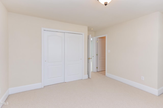 unfurnished bedroom with light colored carpet and a closet