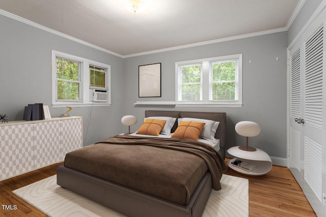 bedroom featuring cooling unit, hardwood / wood-style floors, ornamental molding, and a closet